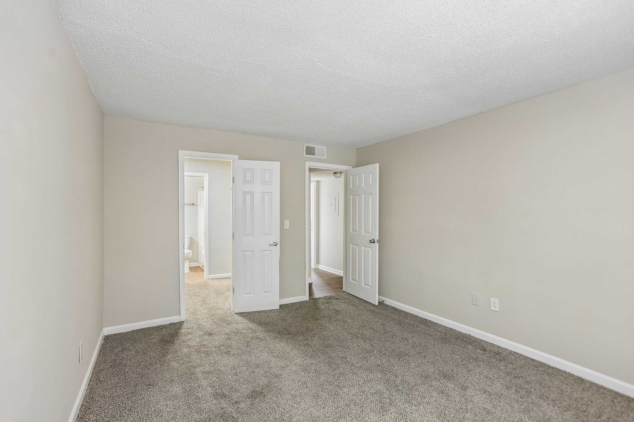 A room with carpeted floor and two open doors.